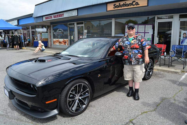 Murray Barnes, a Classic LifeCare home care client in Vancouver, smiling next to his Dodge Challenger Scat Pack